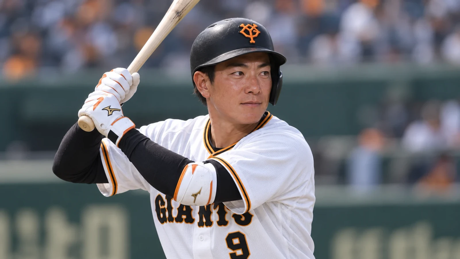 白いユニフォームと黒いヘルメット姿の選手が、バットを構えて打席に立っている。