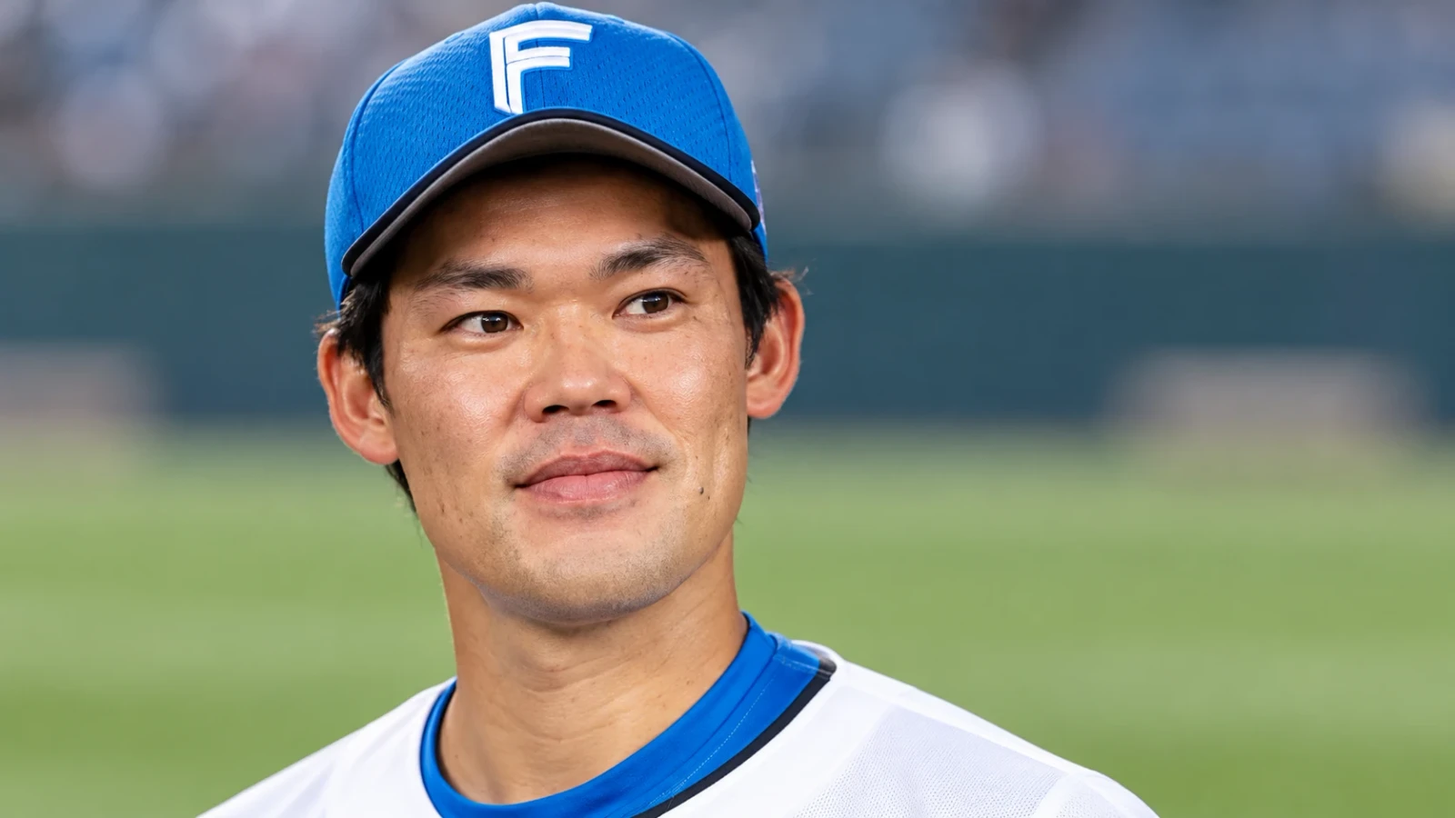 球場で青い野球帽と白いユニフォームを着た選手の上半身