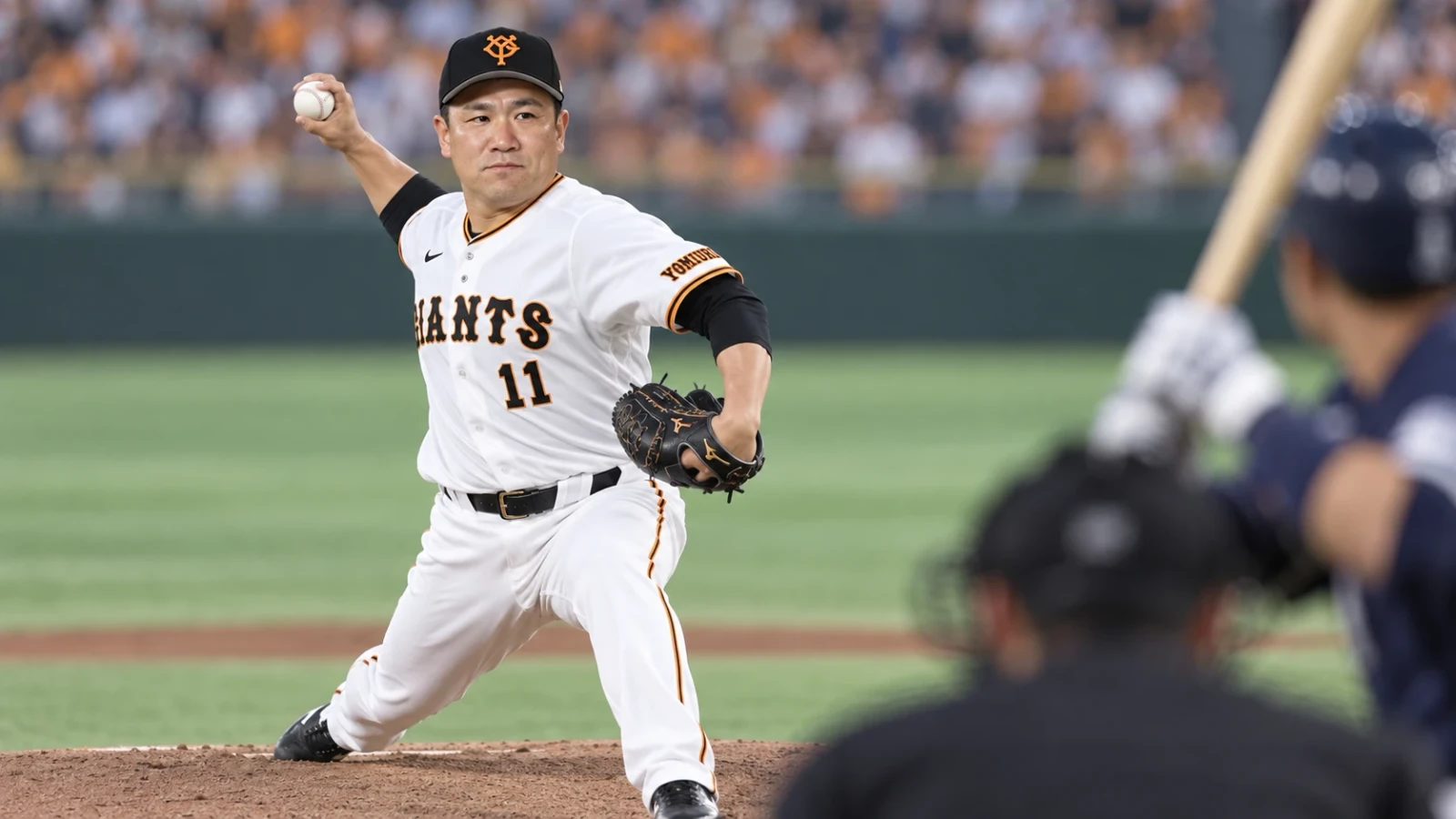 白いユニフォームの投手がマウンドから投球し、手前に捕手と打者がぼけて見える